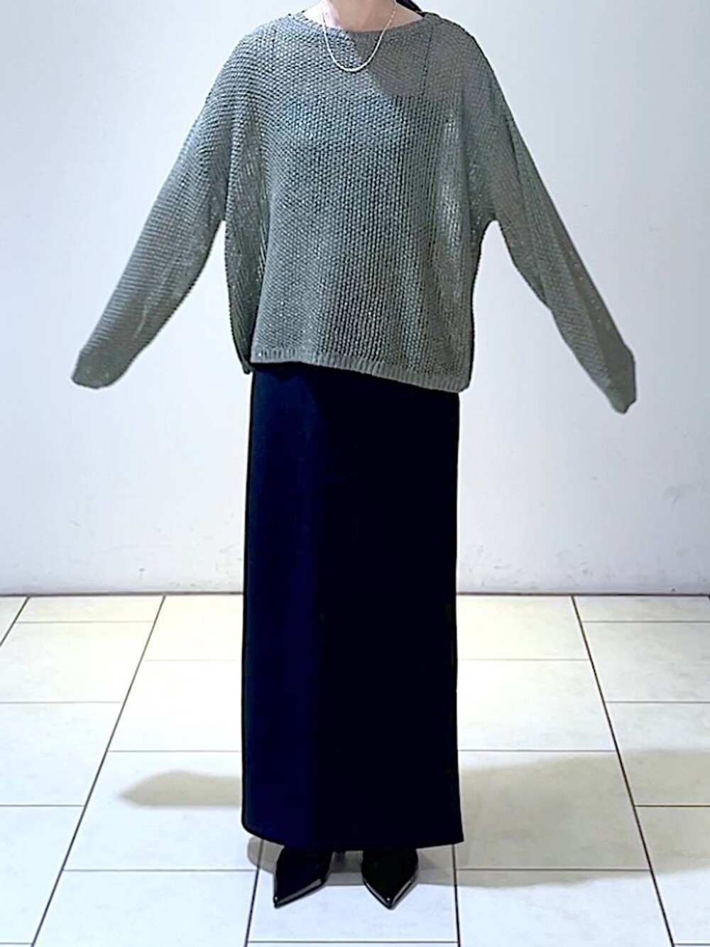 グリーン系のニット/セーター、ブラック系のパンプス、ブラック系のスカートを着用したレディースの秋コーディネートの2枚目の写真