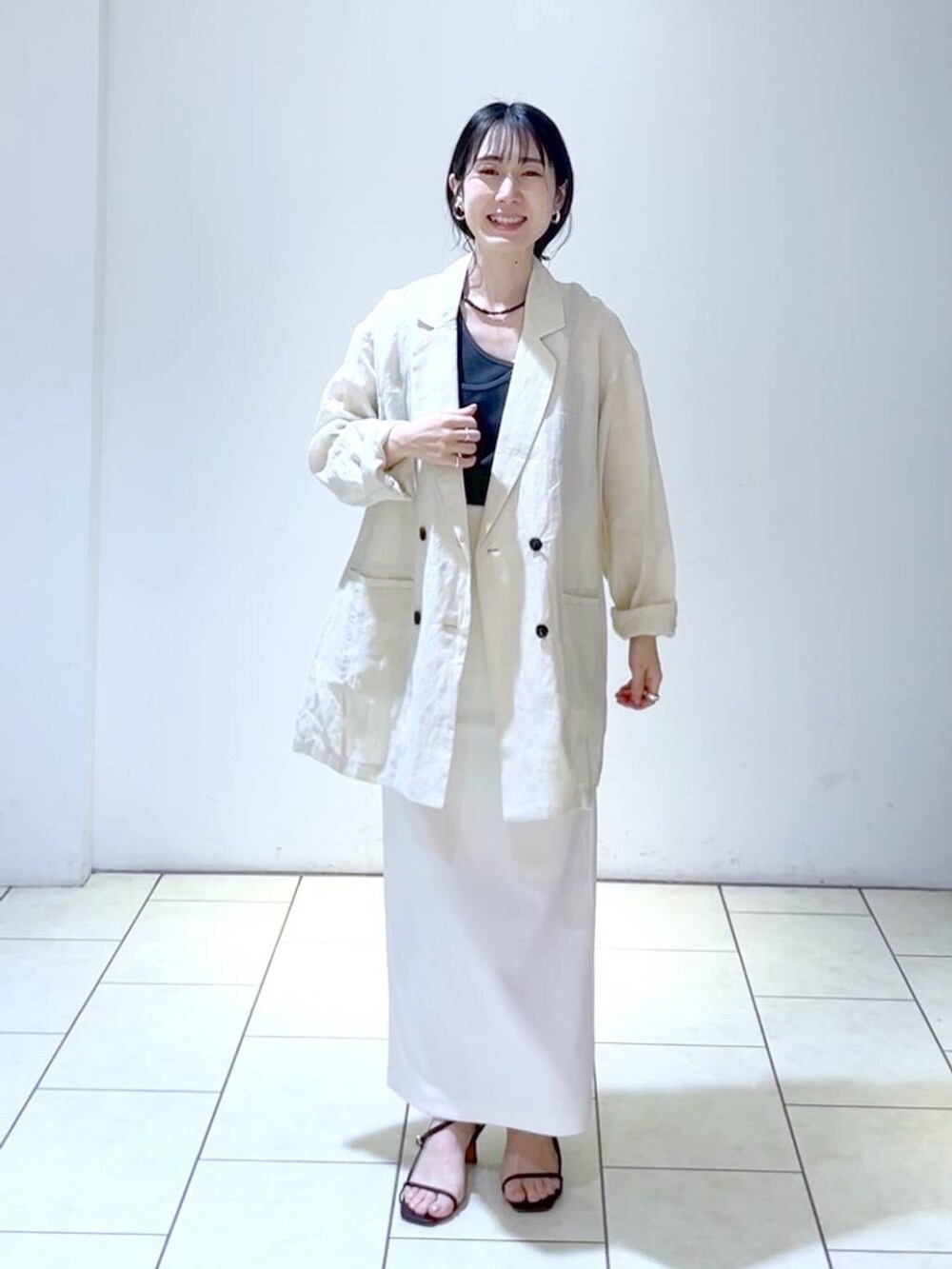 ブラック系のタンクトップ、ホワイト系のスカート、ベージュ系のテーラードジャケットを着用したレディースの夏コーディネートの6枚目の写真