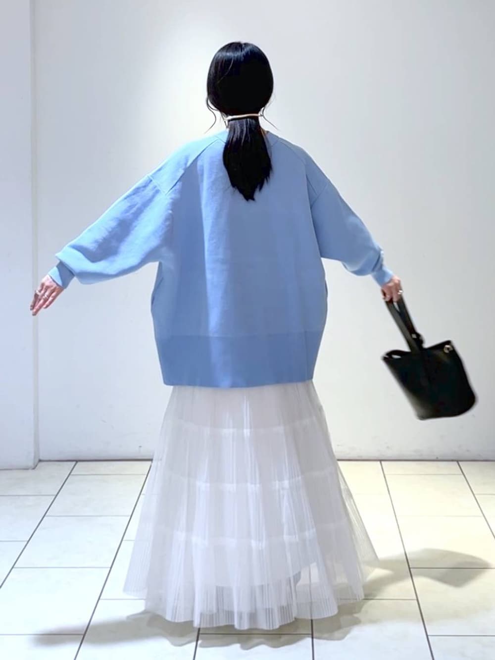 ホワイト系のスカート、ブルー系のカーディガン/ボレロ、ブラック系のショルダーバッグを着用したレディースの冬コーディネートの3枚目の写真