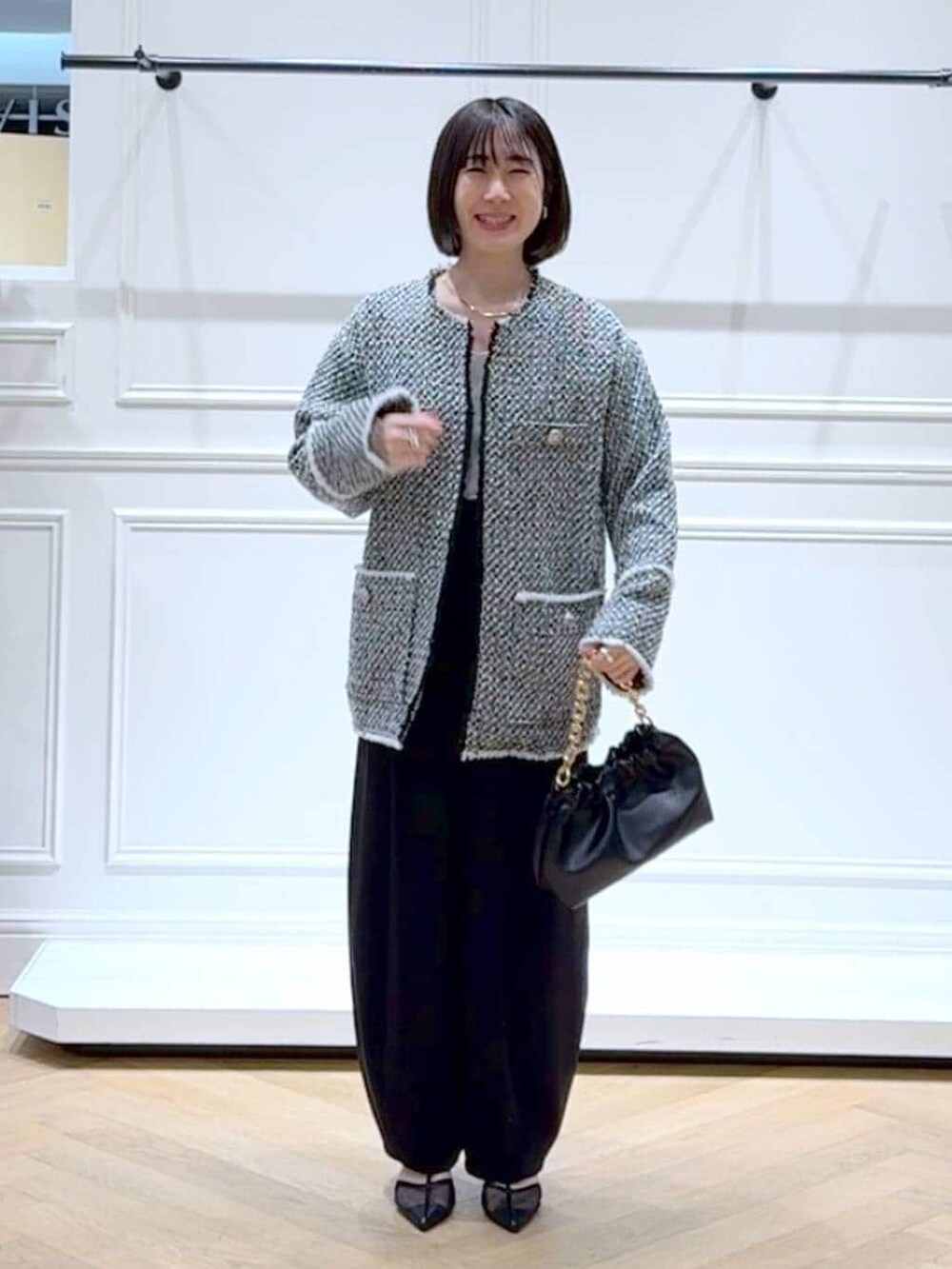 ブラック系のショルダーバッグ、ブラック系のスラックス、ブラック系のノーカラージャケットを着用したレディースの春コーディネートの6枚目の写真