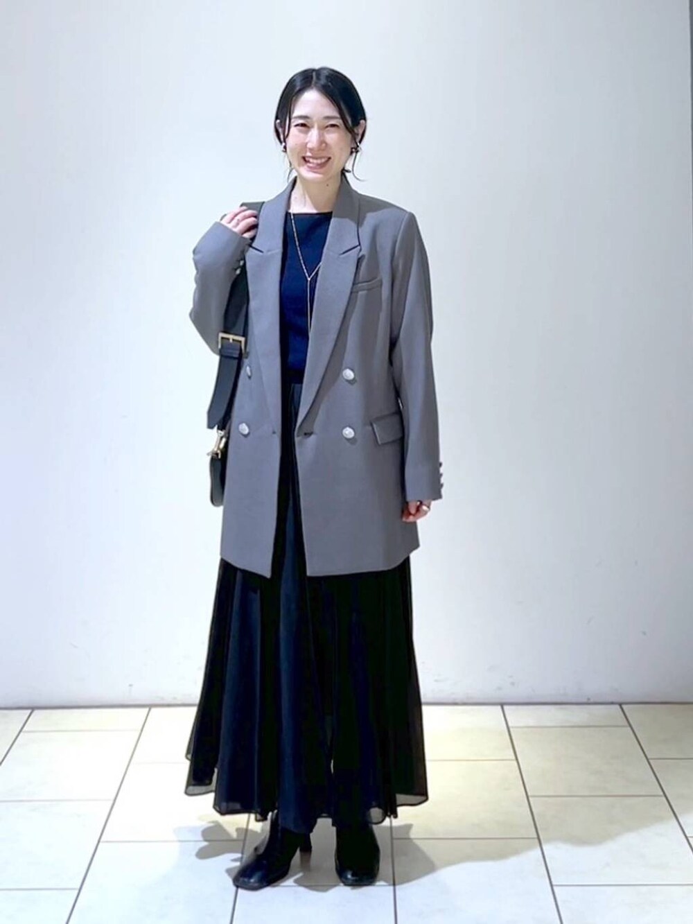 ブルー系のニット/セーター、ブラック系のショルダーバッグ、ブラック系のスカートを着用したレディースの春コーディネートの6枚目の写真