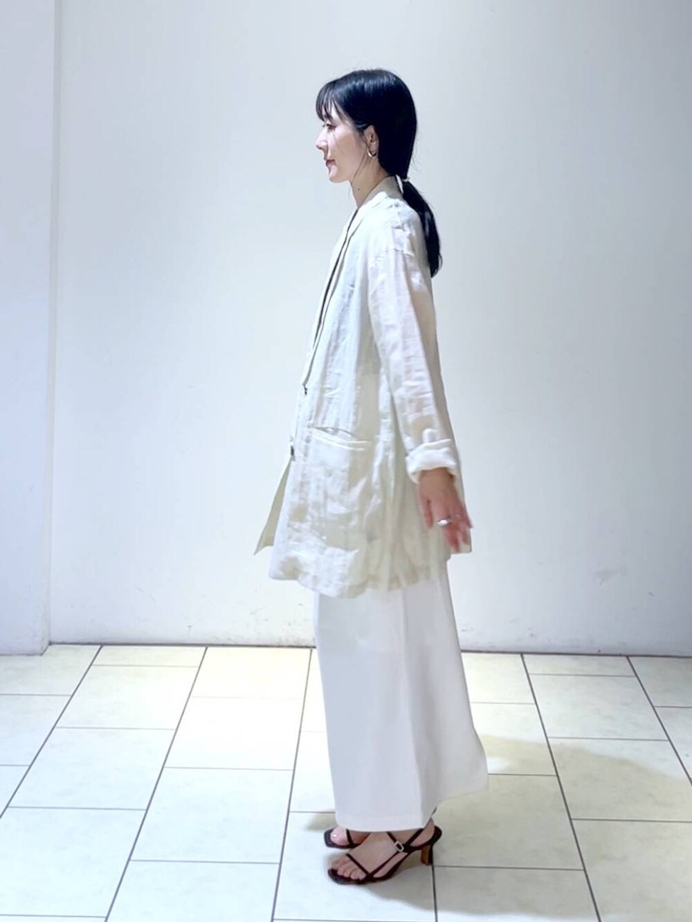 ブラック系のタンクトップ、ホワイト系のスカート、ベージュ系のテーラードジャケットを着用したレディースの夏コーディネートの5枚目の写真