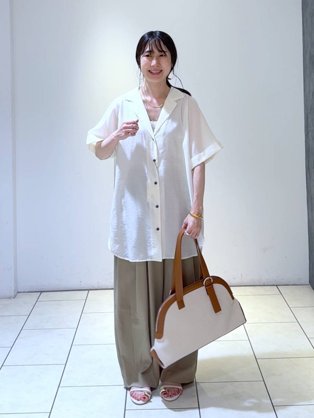 ベージュ系のスラックス、ホワイト系のシャツ/ブラウス、ブラウン系のトートバッグを着用したレディースの春コーディネートの6枚目の写真