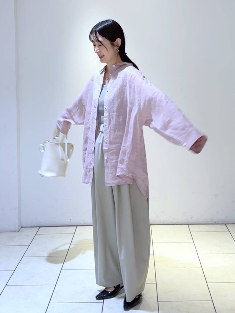 グレー系のタンクトップ、ホワイト系のショルダーバッグ、ブラック系のパンプスを着用したレディースの春コーディネートの5枚目の写真