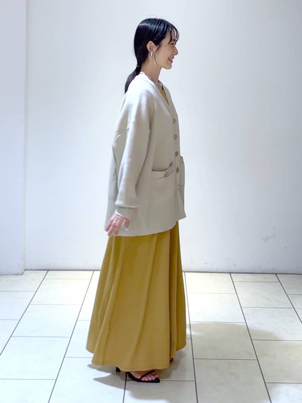 ブラック系のサンダル、オレンジ系のワンピース、ベージュ系のカーディガン/ボレロを着用したレディースの春コーディネートの3枚目の写真