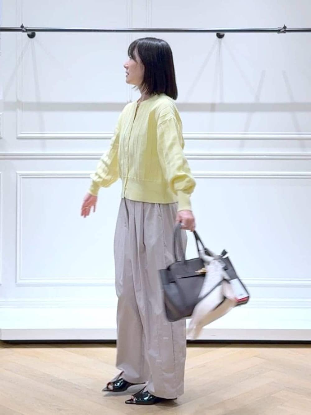 イエロー系のカーディガン/ボレロ、ブラウン系のショルダーバッグ、ブラック系のサンダルを着用したレディースの春コーディネートの5枚目の写真