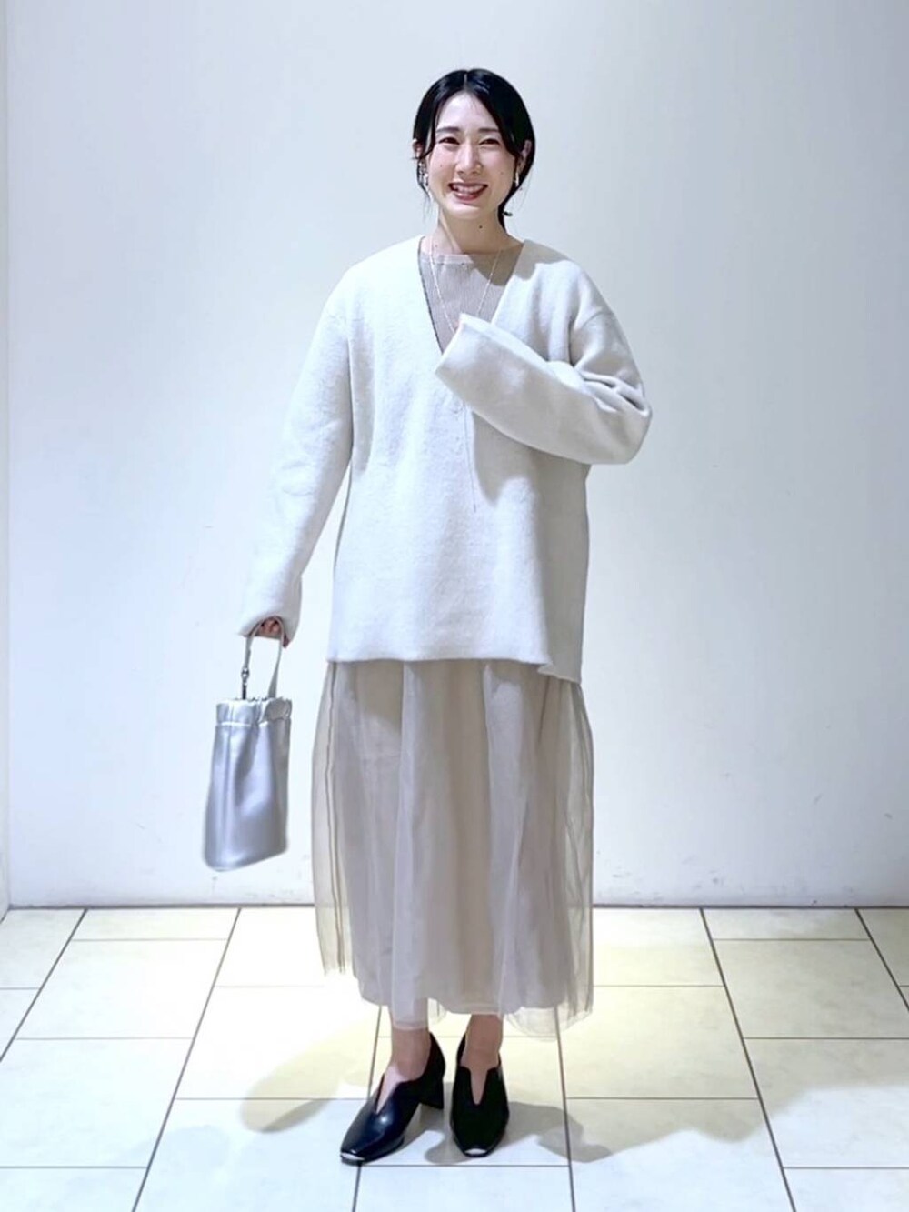 ベージュ系のワンピース、ホワイト系のニット/セーター、ブラック系のパンプスを着用したレディースの春コーディネートの6枚目の写真