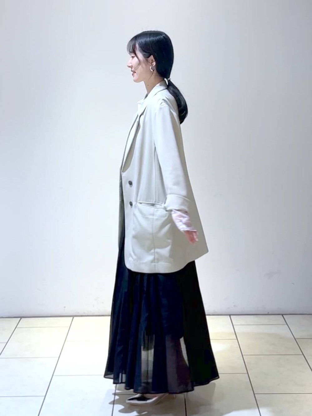 ホワイト系のTシャツ/カットソー、シルバー系のサンダル、ブラック系のスカートを着用したレディースの春コーディネートの5枚目の写真