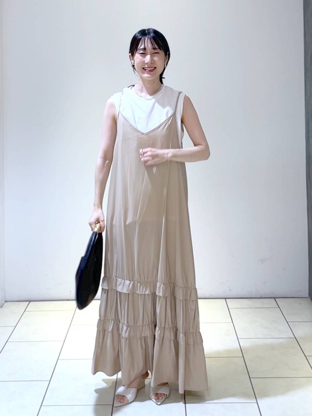 ホワイト系のサンダル、ブラック系のハンドバッグ、ベージュ系のワンピースを着用したレディースの夏コーディネートの6枚目の写真