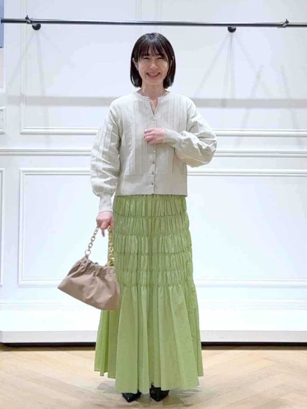 ホワイト系のカーディガン/ボレロ、ベージュ系のショルダーバッグ、ブラック系のパンプスを着用したレディースの春コーディネートの6枚目の写真