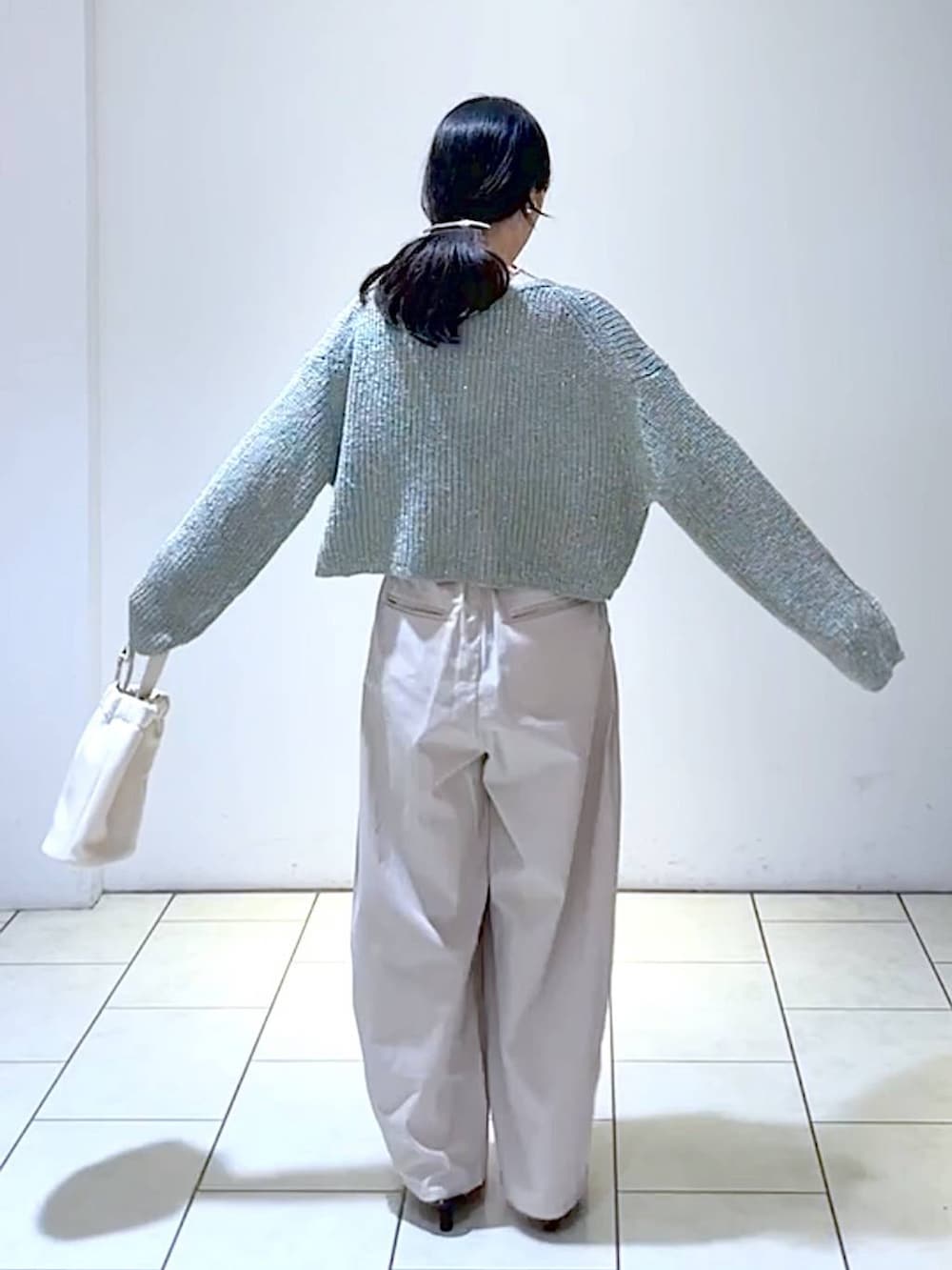 グレー系のカーディガン/ボレロ、ブラック系のパンプス、ホワイト系のショルダーバッグを着用したレディースの秋コーディネートの3枚目の写真