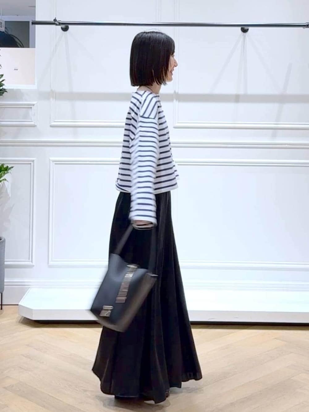 ブラック系のスカート、ブラウン系のローファー、ブラック系のショルダーバッグを着用したレディースの春コーディネートの3枚目の写真