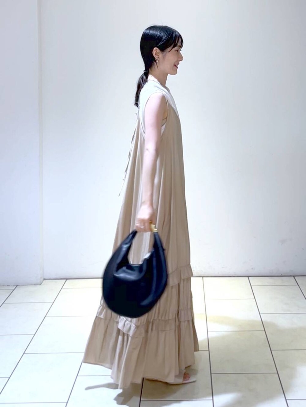 ホワイト系のサンダル、ブラック系のハンドバッグ、ベージュ系のワンピースを着用したレディースの夏コーディネートの3枚目の写真