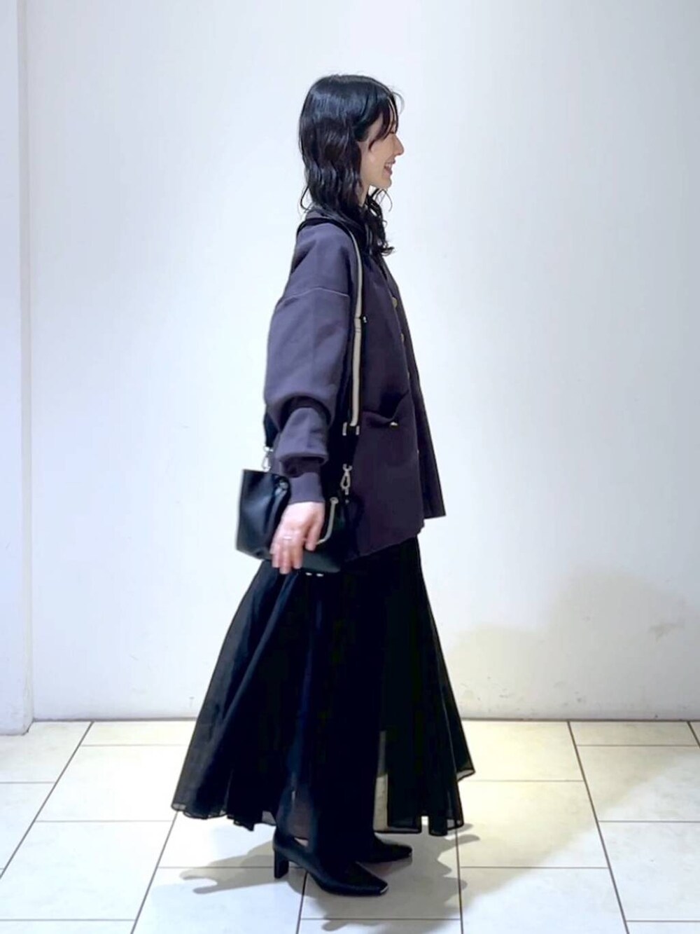 ブラック系のショルダーバッグ、ブラック系のスカート、ブラック系のパンプスを着用したレディースの春コーディネートの3枚目の写真
