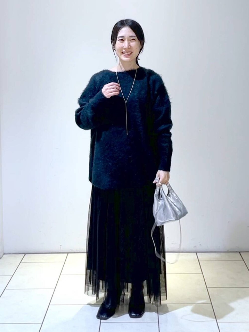 ブラック系のスカート、グリーン系のニット/セーター、シルバー系のショルダーバッグを着用したレディースの冬コーディネートの6枚目の写真