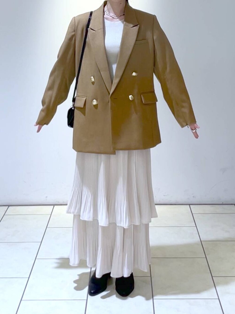 イエロー系のテーラードジャケット、ホワイト系のニット/セーター、ホワイト系のスカートを着用したレディースの秋コーディネートの2枚目の写真