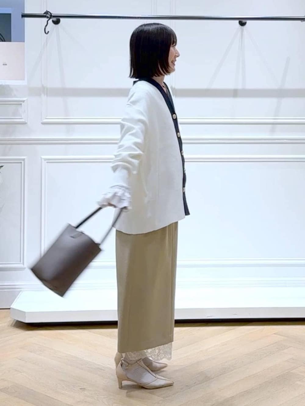 ブラック系のカーディガン/ボレロ、ベージュ系のスカート、ブラウン系のショルダーバッグを着用したレディースの春コーディネートの3枚目の写真