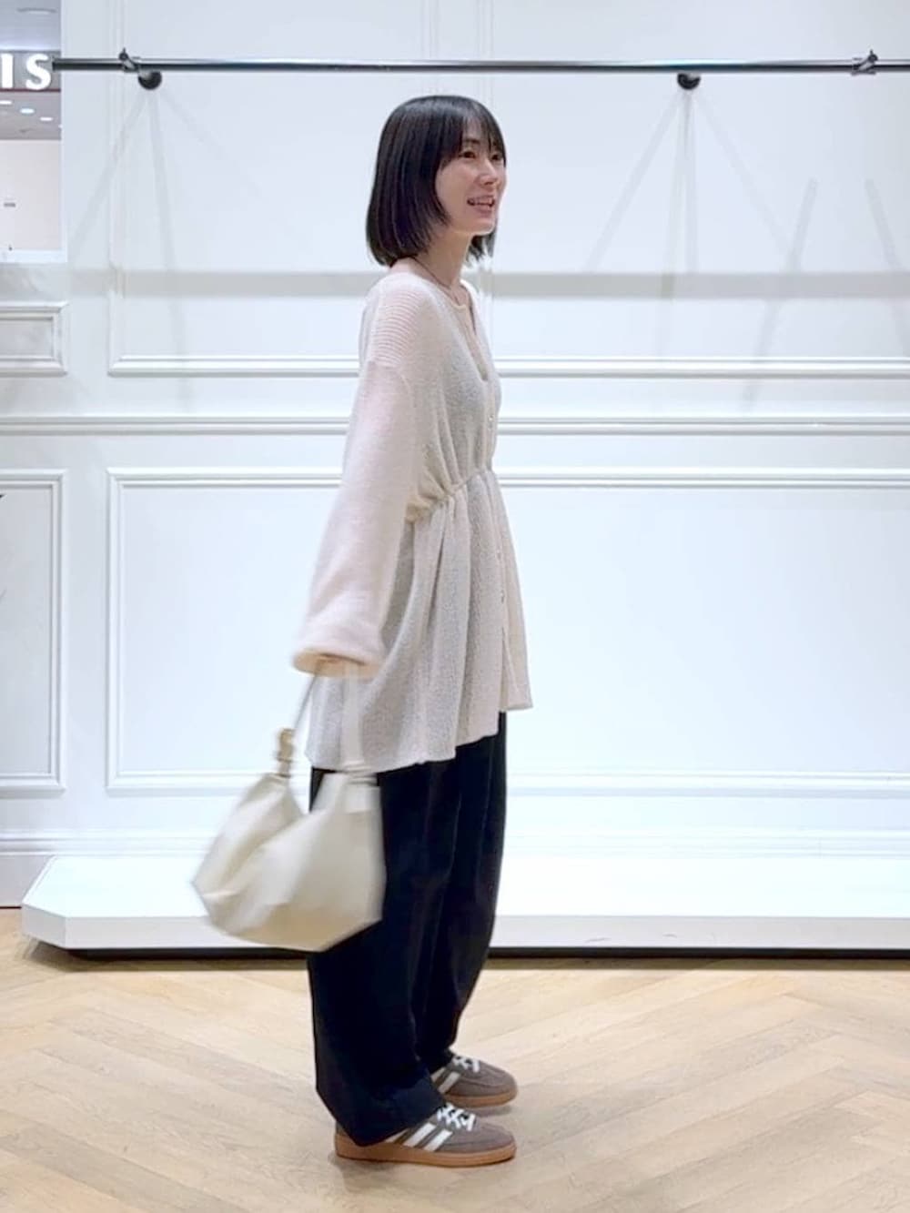 ブラック系のスラックス、ホワイト系のカーディガン/ボレロ、その他のネックレスを着用したレディースの春コーディネートの3枚目の写真