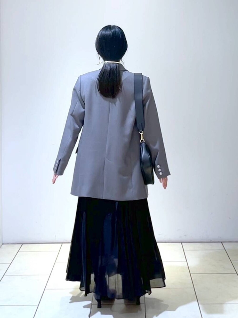 ブルー系のニット/セーター、ブラック系のショルダーバッグ、ブラック系のスカートを着用したレディースの春コーディネートの4枚目の写真