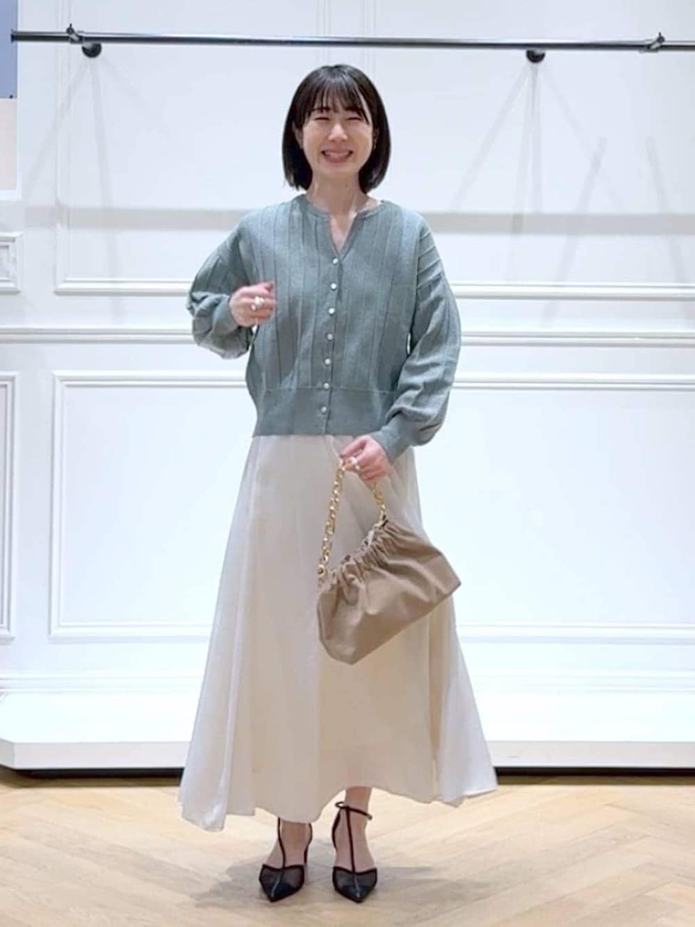 グリーン系のカーディガン/ボレロ、ベージュ系のショルダーバッグ、ホワイト系のスカートを着用したレディースの春コーディネートの6枚目の写真