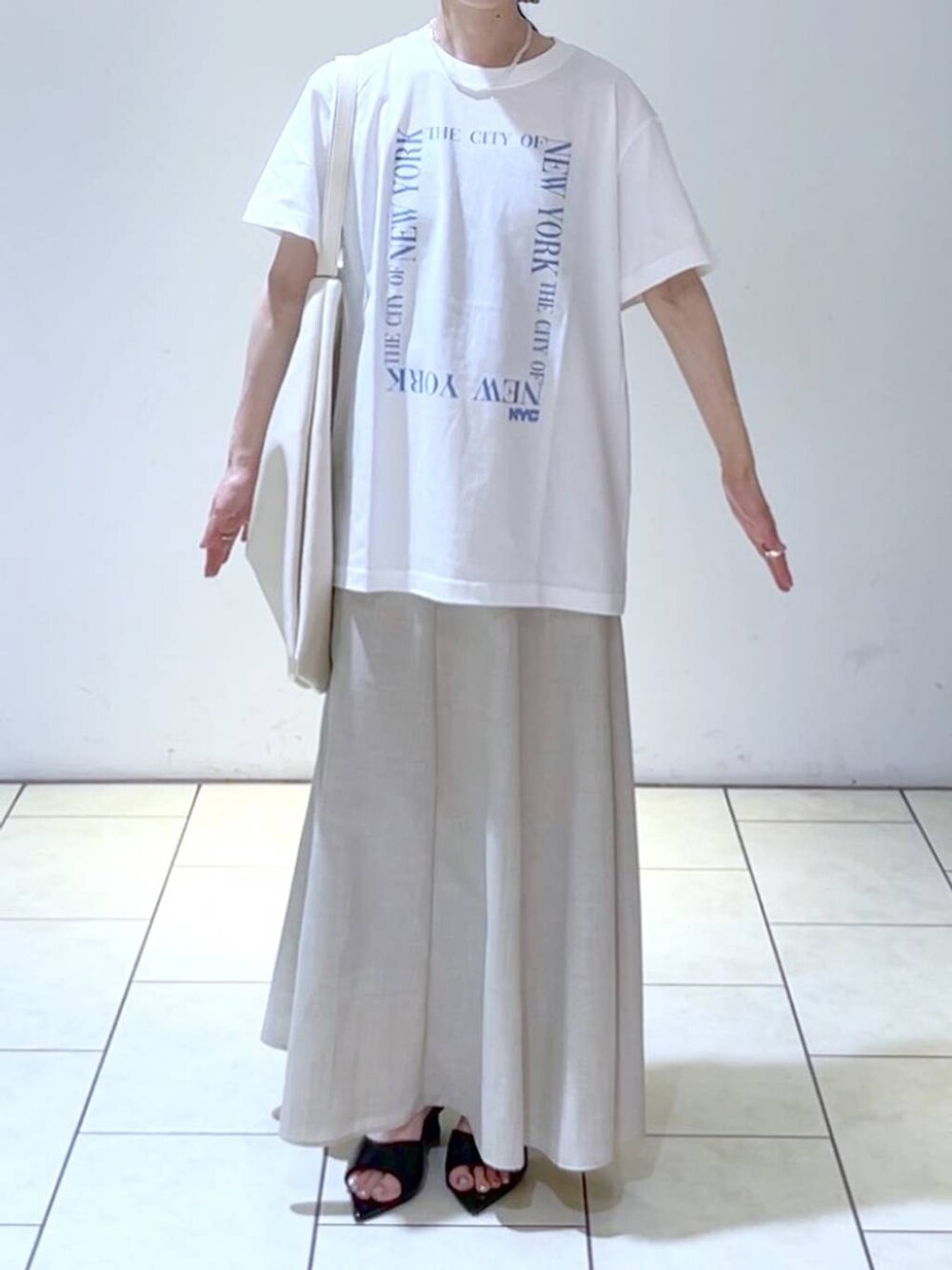 ブラック系のサンダル、ホワイト系のトートバッグ、ベージュ系のスカートを着用したレディースの夏コーディネートの2枚目の写真