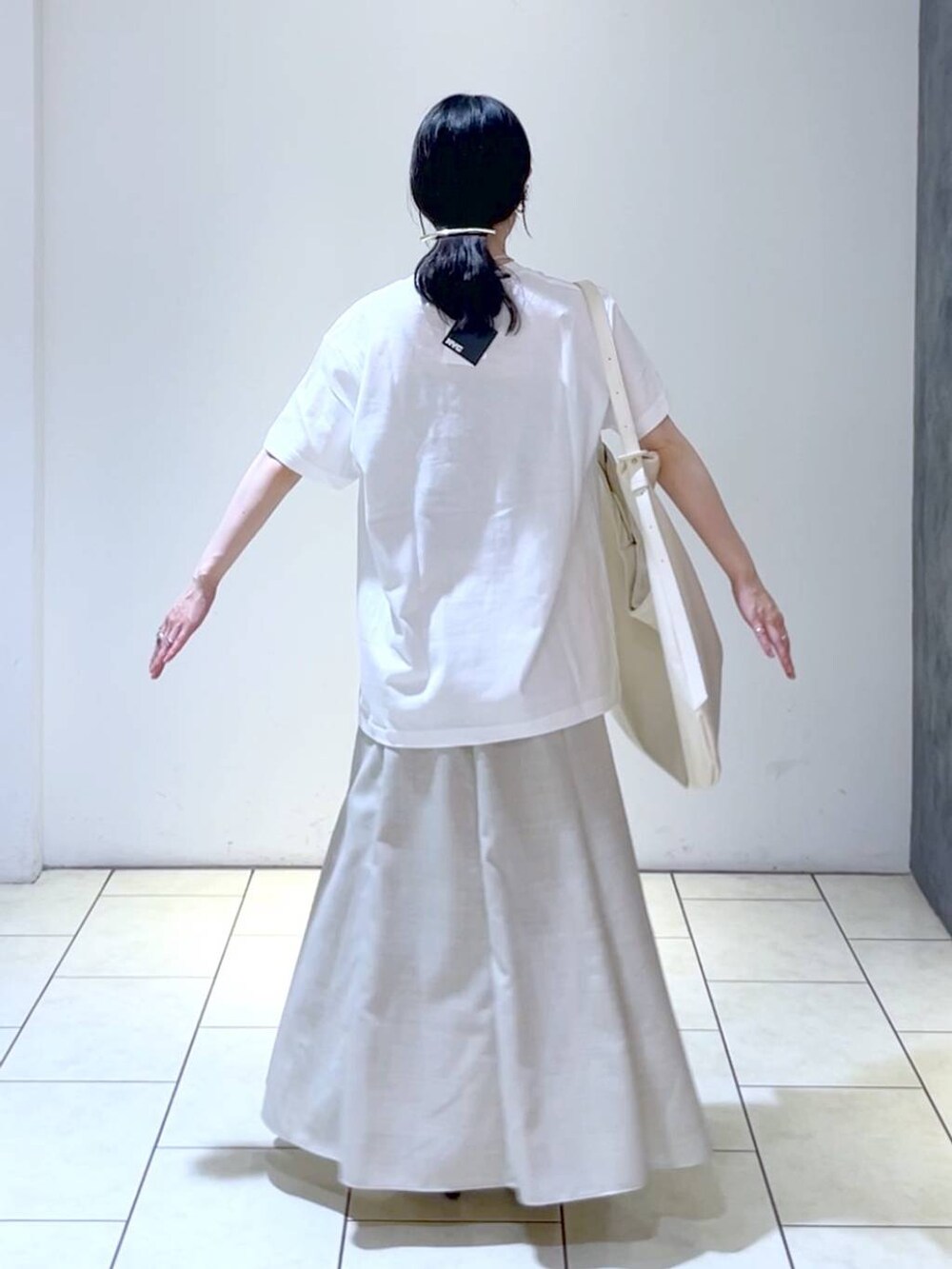 ブラック系のサンダル、ホワイト系のトートバッグ、ベージュ系のスカートを着用したレディースの夏コーディネートの4枚目の写真