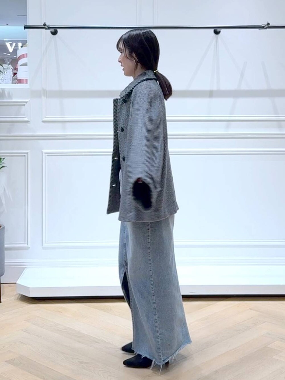 ホワイト系のニット/セーター、ブルー系のデニムスカート、ブラック系のブーツを着用したレディースの秋コーディネートの5枚目の写真