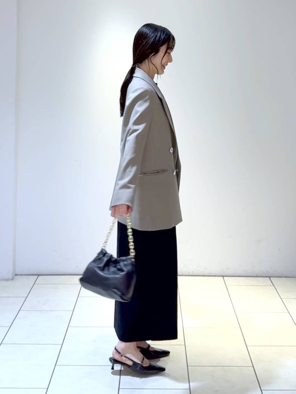 ホワイト系のワンピース、ブラック系のパンプス、グレー系のテーラードジャケットを着用したレディースの冬コーディネートの4枚目の写真