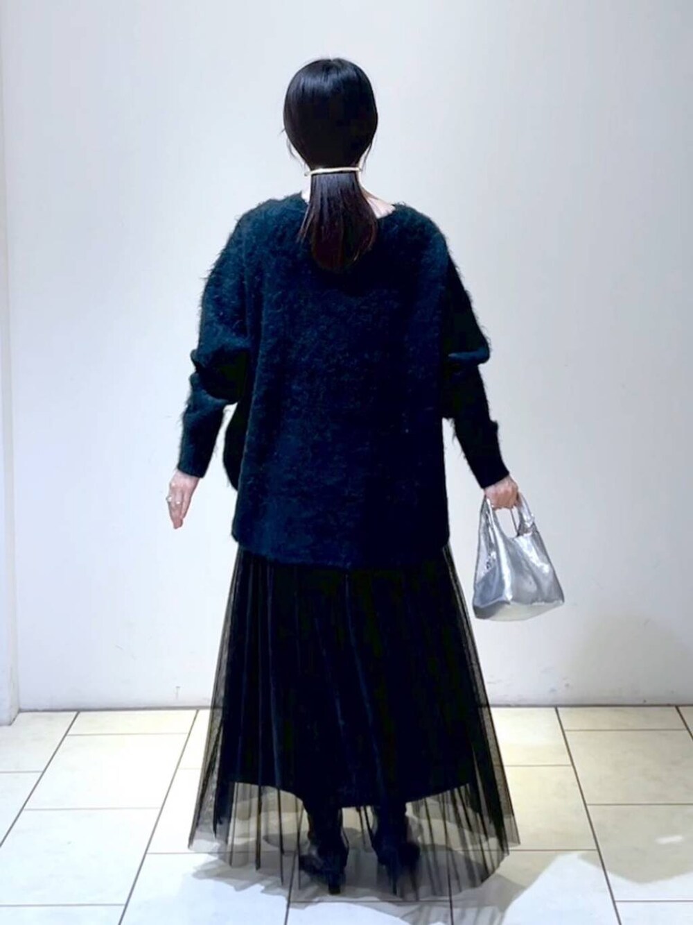 ブラック系のスカート、グリーン系のニット/セーター、シルバー系のショルダーバッグを着用したレディースの冬コーディネートの4枚目の写真