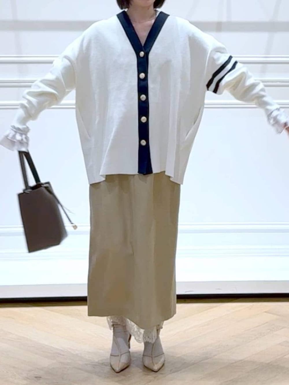 ブラック系のカーディガン/ボレロ、ベージュ系のスカート、ブラウン系のショルダーバッグを着用したレディースの春コーディネートの2枚目の写真