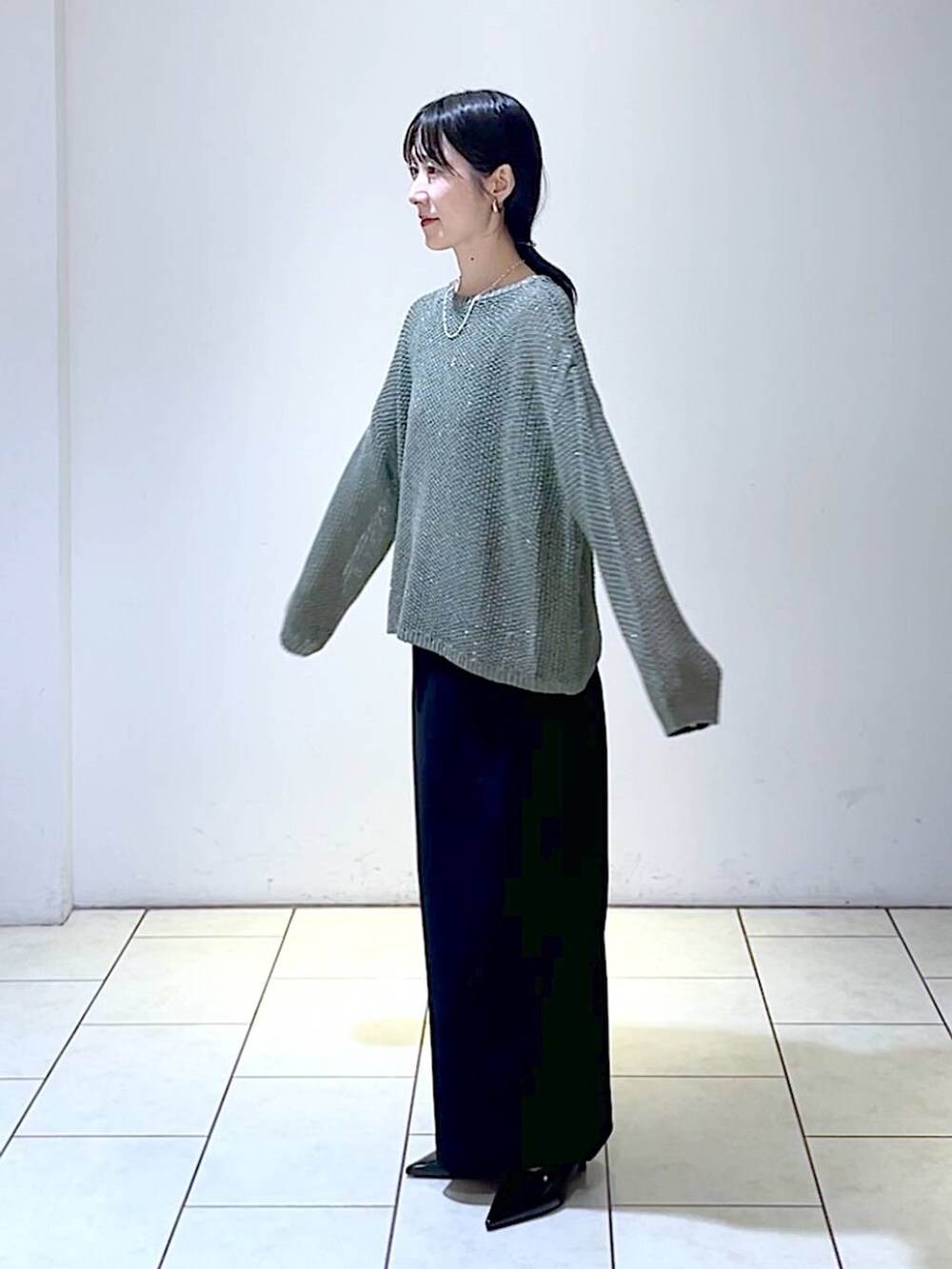 グリーン系のニット/セーター、ブラック系のパンプス、ブラック系のスカートを着用したレディースの秋コーディネートの5枚目の写真