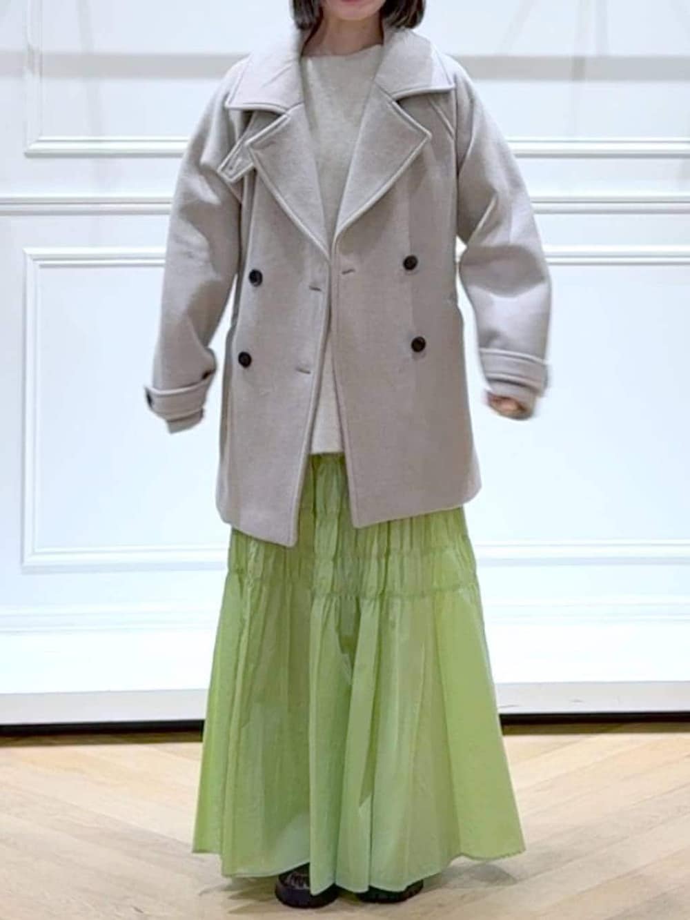 ベージュ系のピーコート、ホワイト系のニット/セーター、ブラウン系のローファーを着用したレディースの冬コーディネートの2枚目の写真