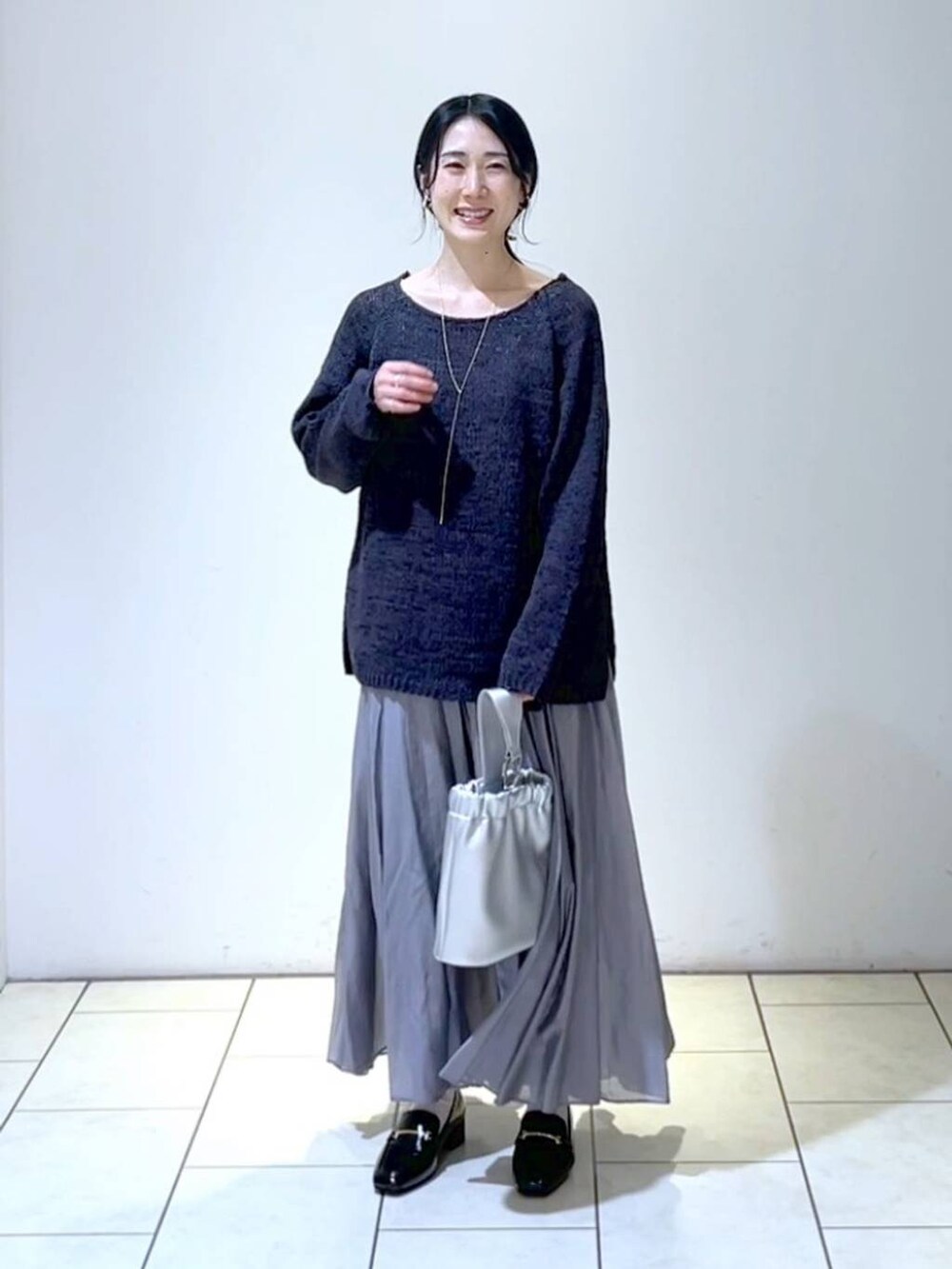 ブラック系のローファー、グレー系のスカート、シルバー系のショルダーバッグを着用したレディースの春コーディネートの6枚目の写真