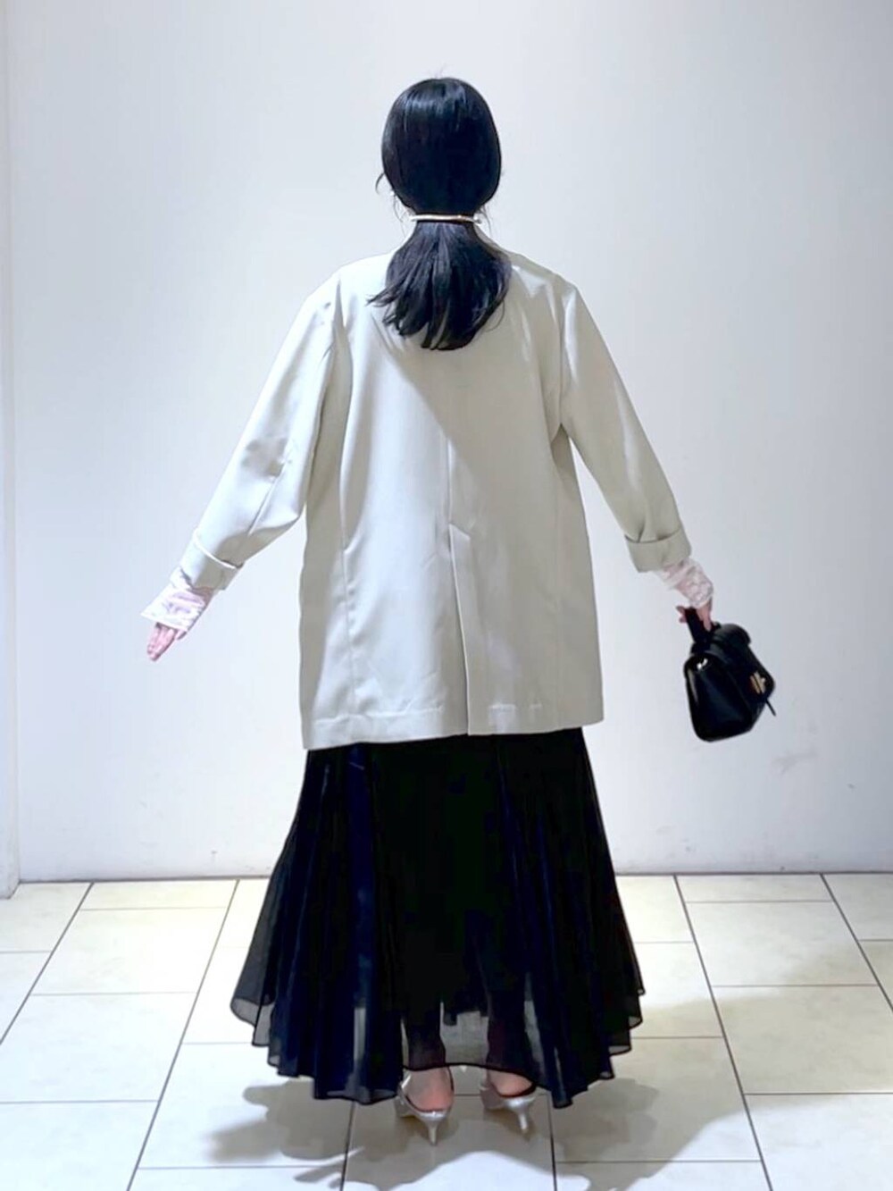 ホワイト系のTシャツ/カットソー、シルバー系のサンダル、ブラック系のスカートを着用したレディースの春コーディネートの4枚目の写真