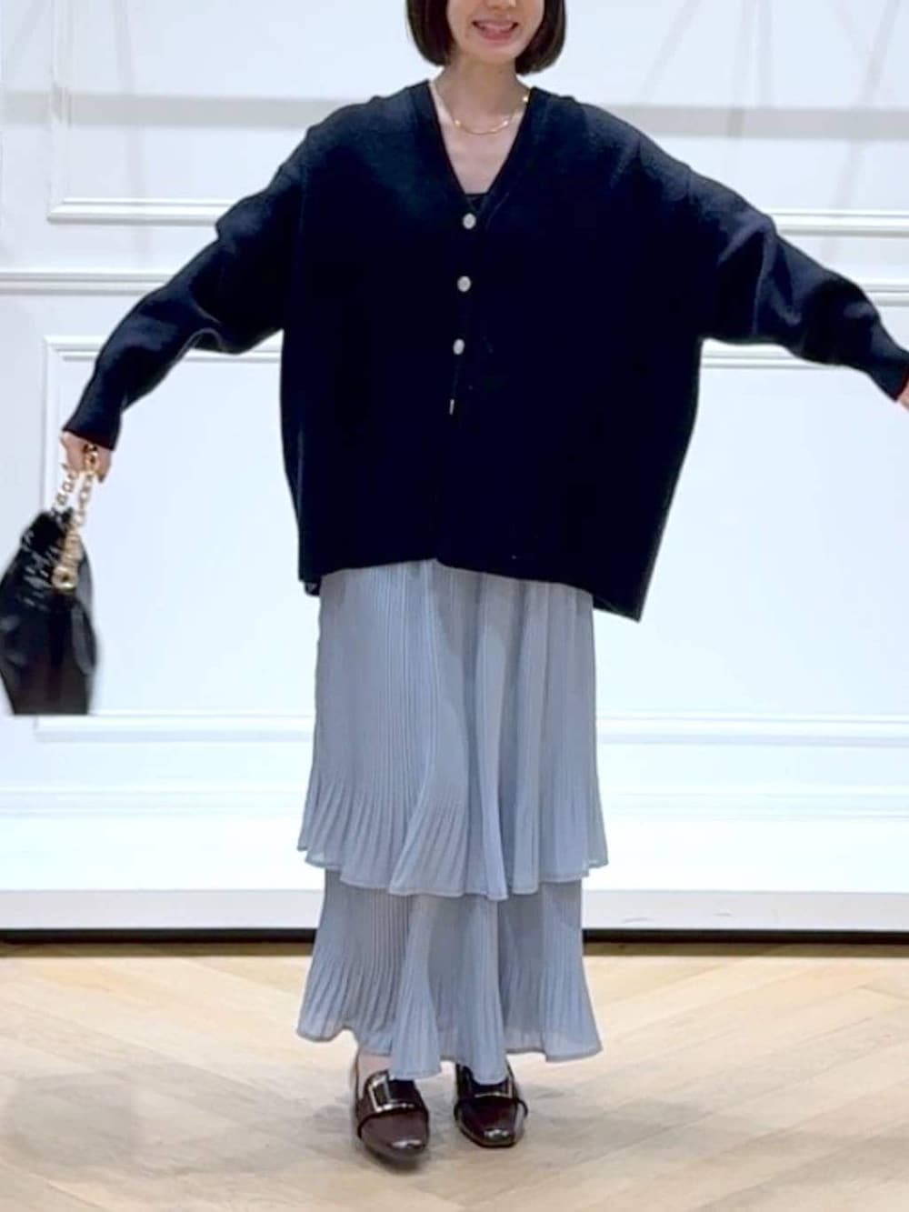 ブルー系のスカート、ブルー系のカーディガン/ボレロ、ブラック系のショルダーバッグを着用したレディースの春コーディネートの2枚目の写真