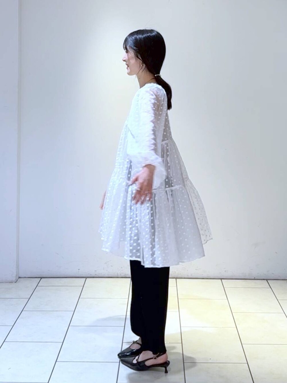 ブラック系のパンプス、ブラック系のスカート、ホワイト系のワンピースを着用したレディースの春コーディネートの5枚目の写真