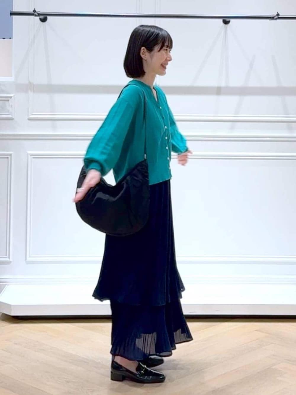 ブルー系のスカート、グリーン系のカーディガン/ボレロ、ブラック系のローファーを着用したレディースの春コーディネートの3枚目の写真