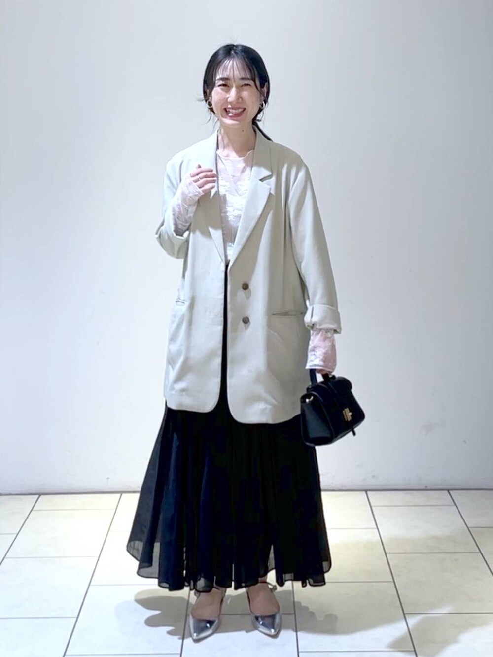 ホワイト系のTシャツ/カットソー、シルバー系のサンダル、ブラック系のスカートを着用したレディースの春コーディネートの6枚目の写真