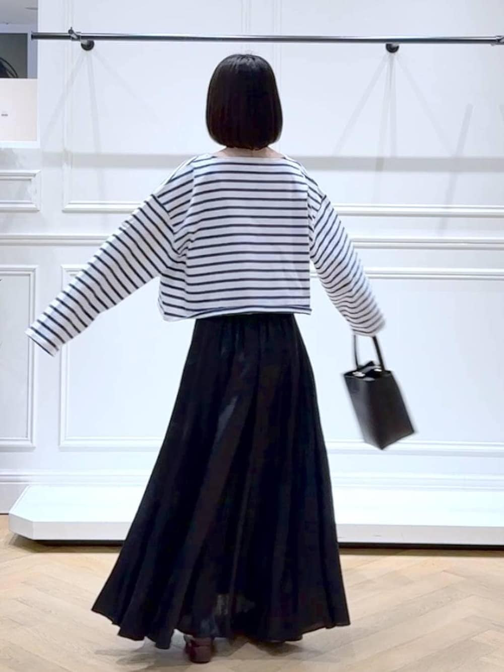 ブラック系のスカート、ブラウン系のローファー、ブラック系のショルダーバッグを着用したレディースの春コーディネートの4枚目の写真