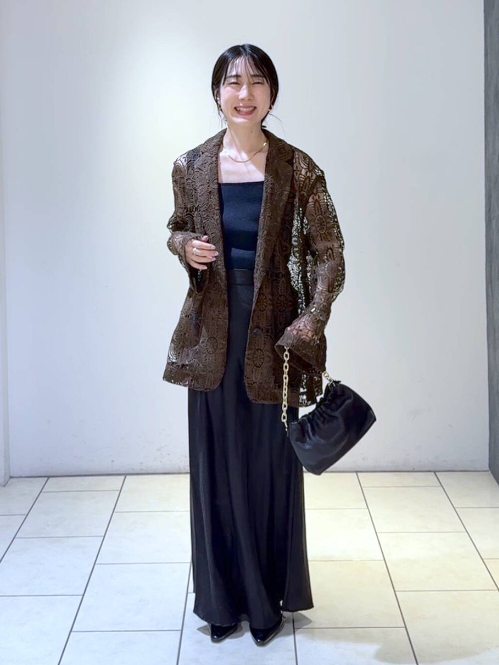 ブルー系のタンクトップ、ブラック系のスカート、ブラック系のパンプスを着用したレディースの春コーディネートの6枚目の写真