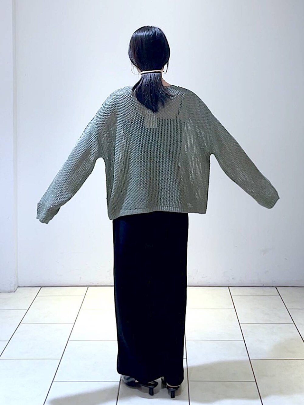 グリーン系のニット/セーター、ブラック系のパンプス、ブラック系のスカートを着用したレディースの秋コーディネートの4枚目の写真