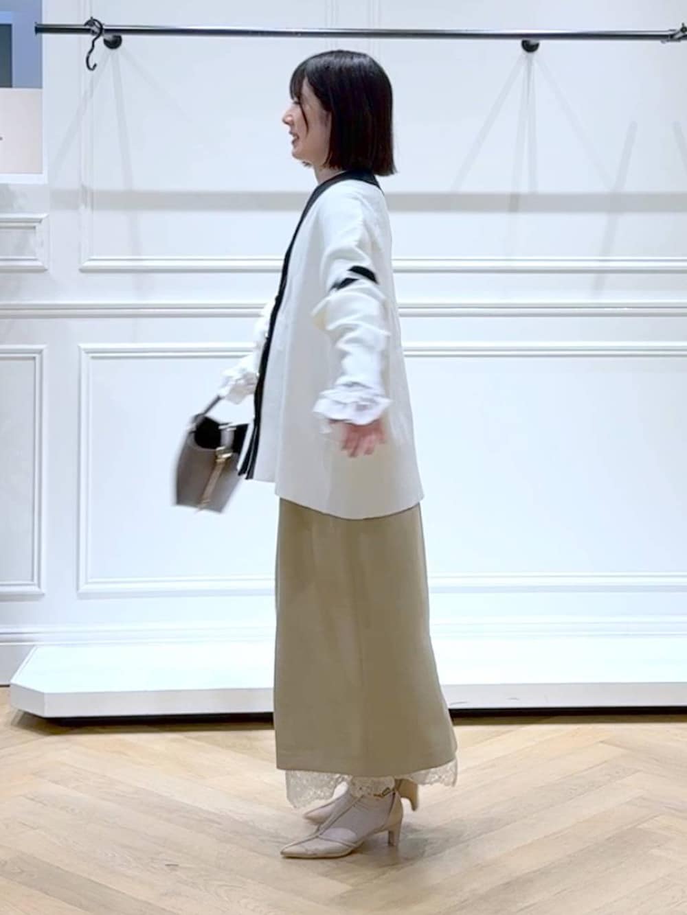 ブラック系のカーディガン/ボレロ、ベージュ系のスカート、ブラウン系のショルダーバッグを着用したレディースの春コーディネートの5枚目の写真