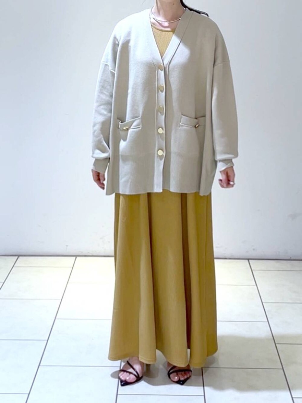 ブラック系のサンダル、オレンジ系のワンピース、ベージュ系のカーディガン/ボレロを着用したレディースの春コーディネートの2枚目の写真