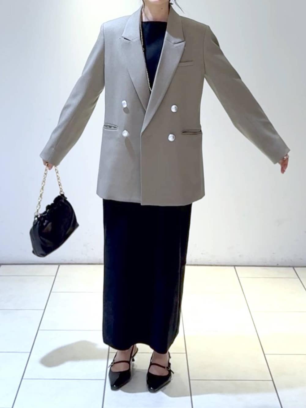 ホワイト系のワンピース、ブラック系のパンプス、グレー系のテーラードジャケットを着用したレディースの冬コーディネートの3枚目の写真