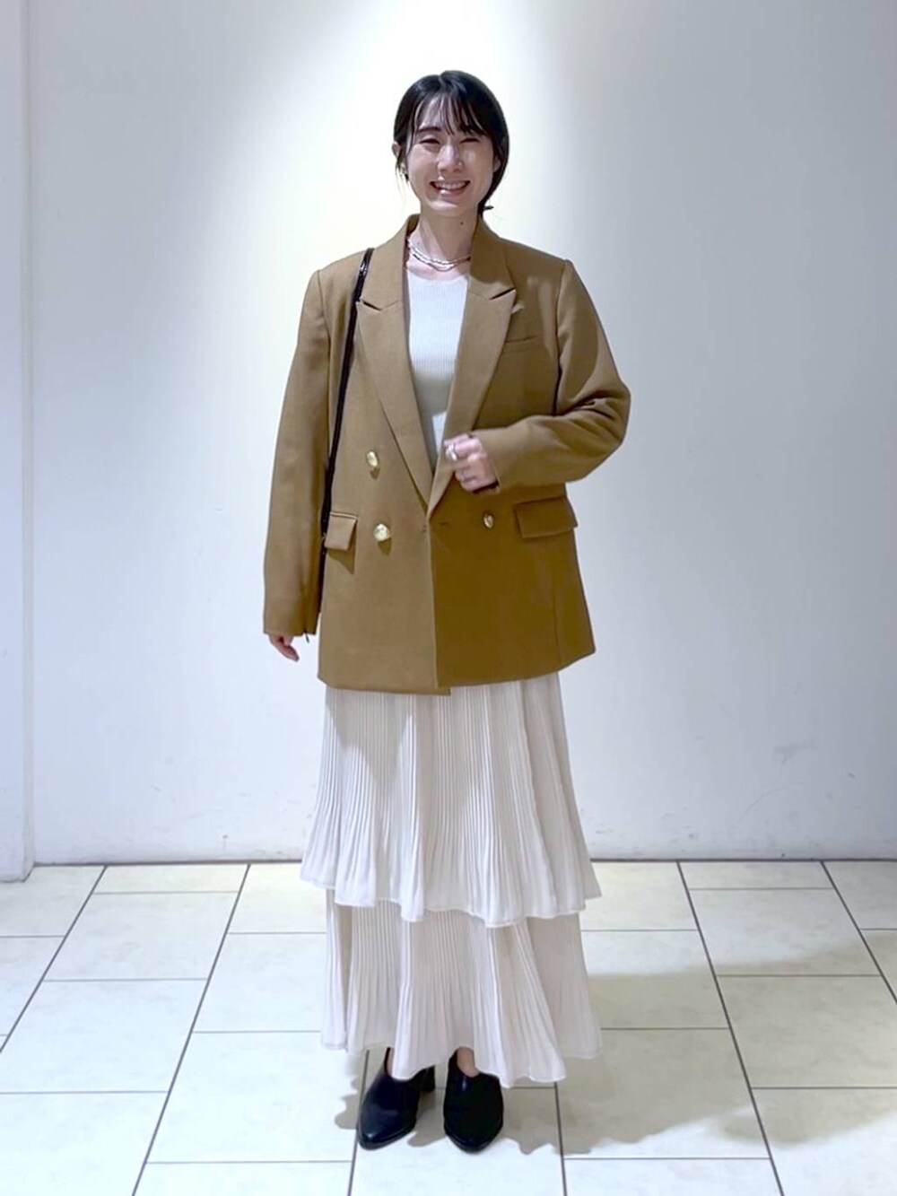 イエロー系のテーラードジャケット、ホワイト系のニット/セーター、ホワイト系のスカートを着用したレディースの秋コーディネートの6枚目の写真