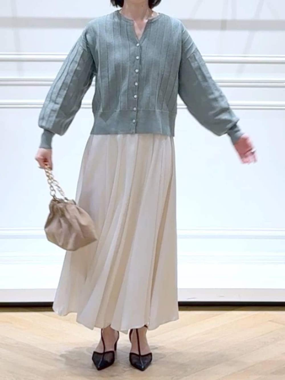 グリーン系のカーディガン/ボレロ、ベージュ系のショルダーバッグ、ホワイト系のスカートを着用したレディースの春コーディネートの2枚目の写真