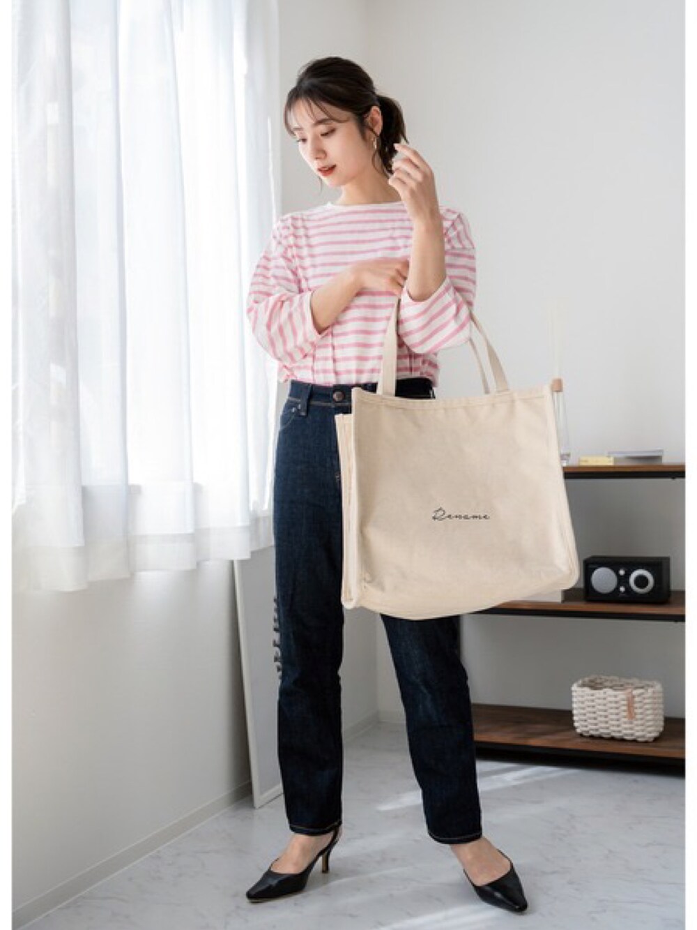 ベージュ系のトートバッグ、ブルー系のベスト、グレー系のスニーカーを着用したレディースの夏コーディネートの2枚目の写真