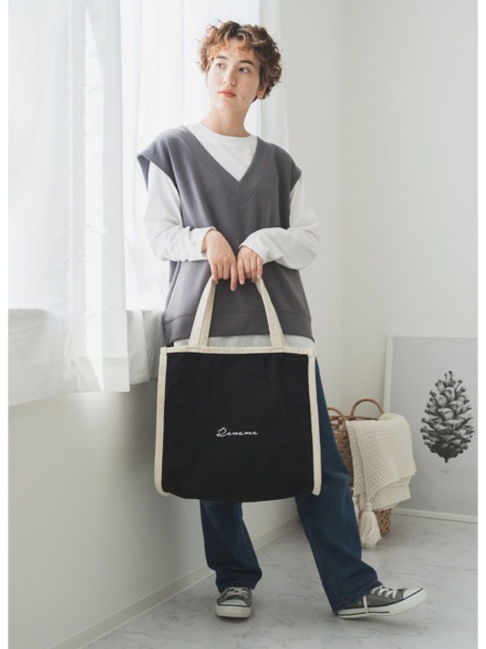 ベージュ系のトートバッグ、ブルー系のベスト、グレー系のスニーカーを着用したレディースの夏コーディネートの3枚目の写真