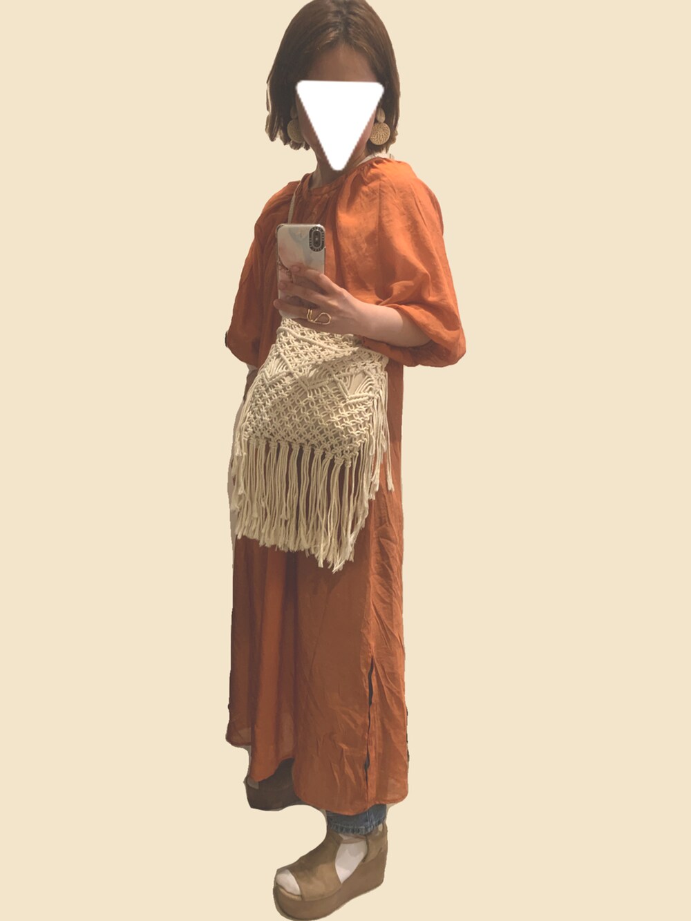 オレンジ系のワンピース、ブルー系のデニムパンツ、ベージュ系のショルダーバッグを着用したレディースの春コーディネートの2枚目の写真