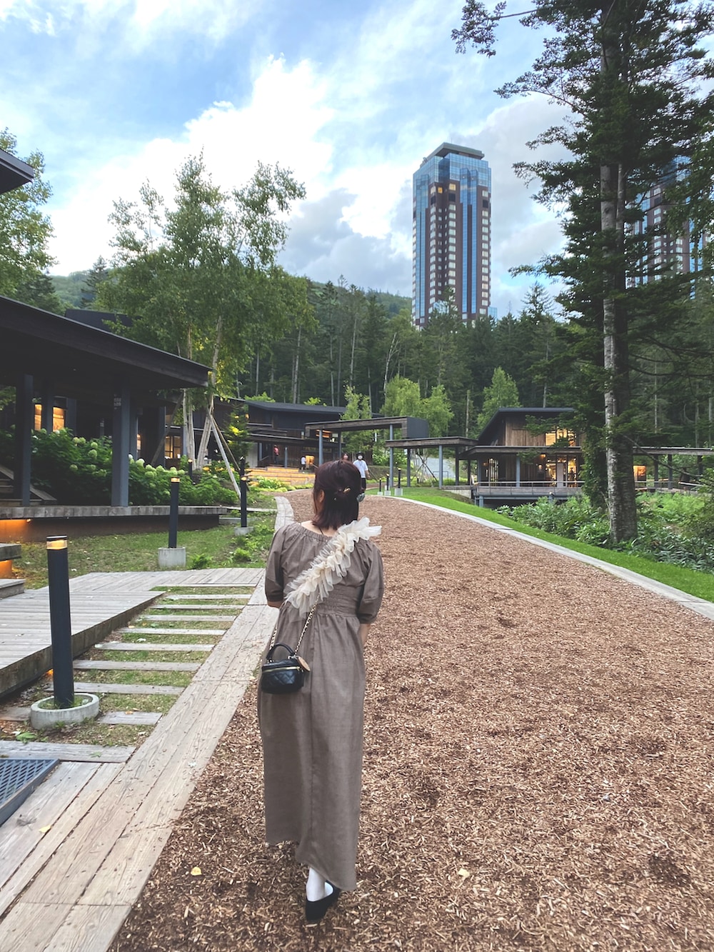 ブラウン系のワンピース、ブラック系のバレエシューズ、ブラック系のショルダーバッグを着用したレディースの秋コーディネートの2枚目の写真